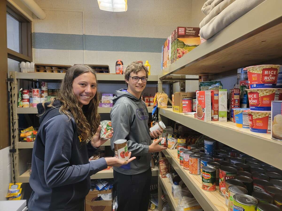 Student council members Grace Wolfe (sophomore) and Tucker Hubbard (senior) stock the shelves of the food pantry at Frankfort High School. 