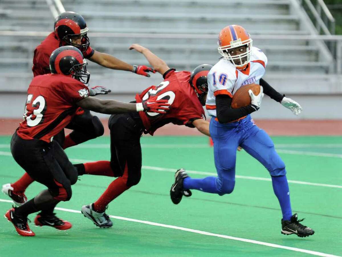 Danbury's #10 Keishaun Fernandez evades three Central players, during football action at Central's Kennedy Stadium in Bridgeport, Conn. on Friday October 1, 2010.