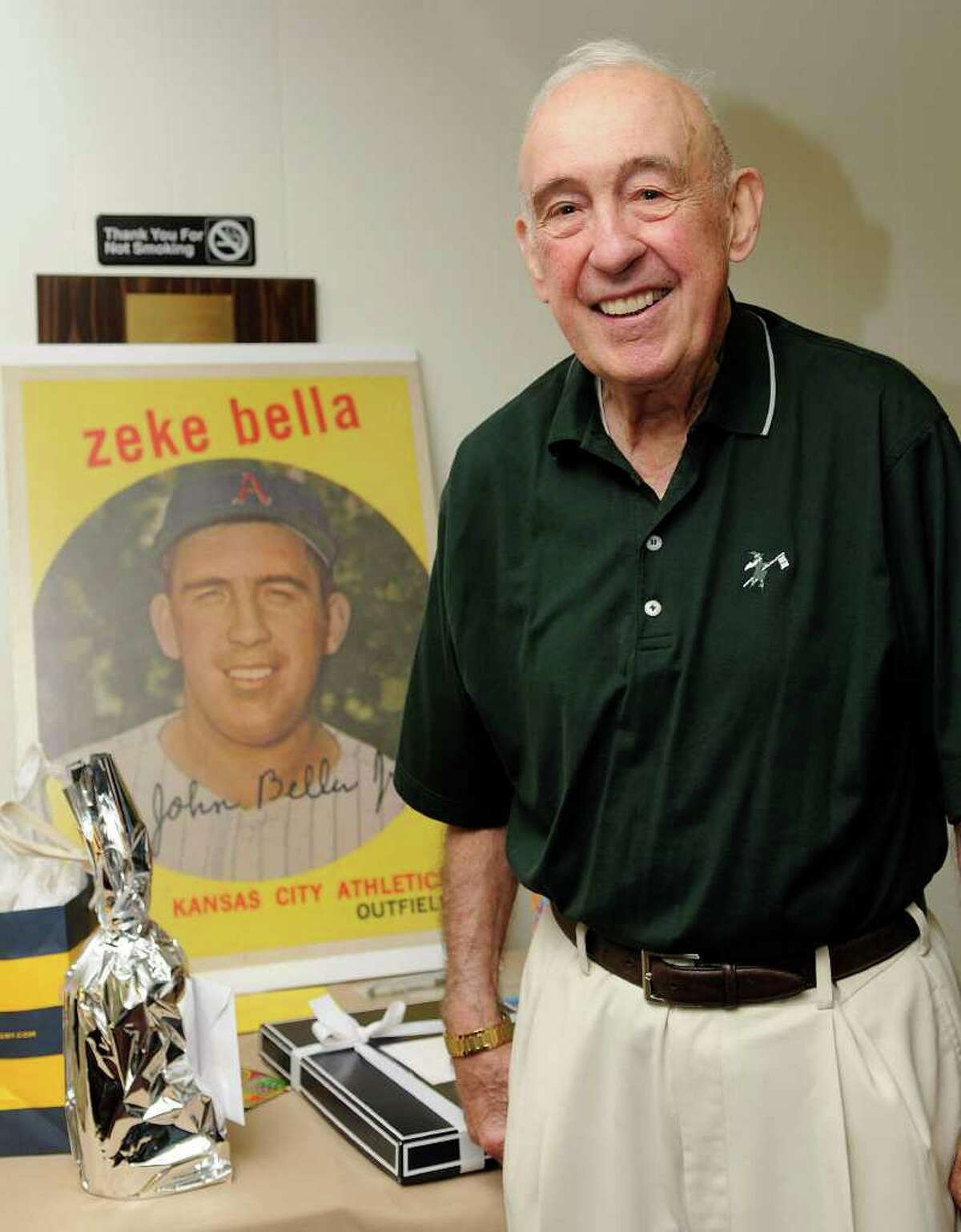 Cos Cob's John "Zeke" Bella, former outfielder for the New York Yankees and Kansas City Athletics, stands in front of a replica of his baseball card during his 80th birthday party with friends and family at the St. Lawrence Club in Cos Cob in August.