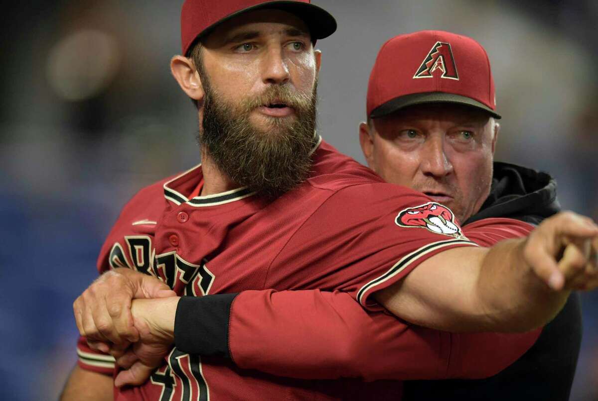 Arizona Diamondbacks' pitcher Madison Bumgarner, left, is restrained by bench coach Jeff Banister while arguing with umpires after the first inning of a baseball game against the against the Miami Marlins, Wednesday, May 4, 2022, in Miami. (AP Photo/Jim Rassol)