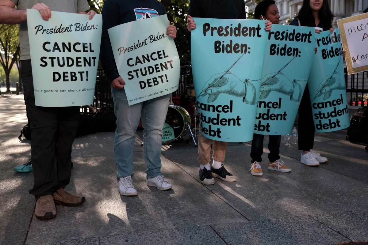 Activists hold signs as they attend a Student Loan Forgiveness rally last month. President Joe Biden should offer a tightly focused form of debt cancellation.