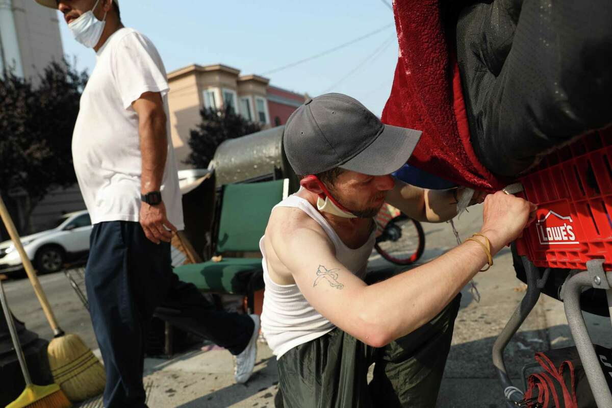 Allen “AJ” Alexander ties a blanket to a cart as he packs up his belongings before relocating from a homeless encampment on 19th Street in San Francisco in August.