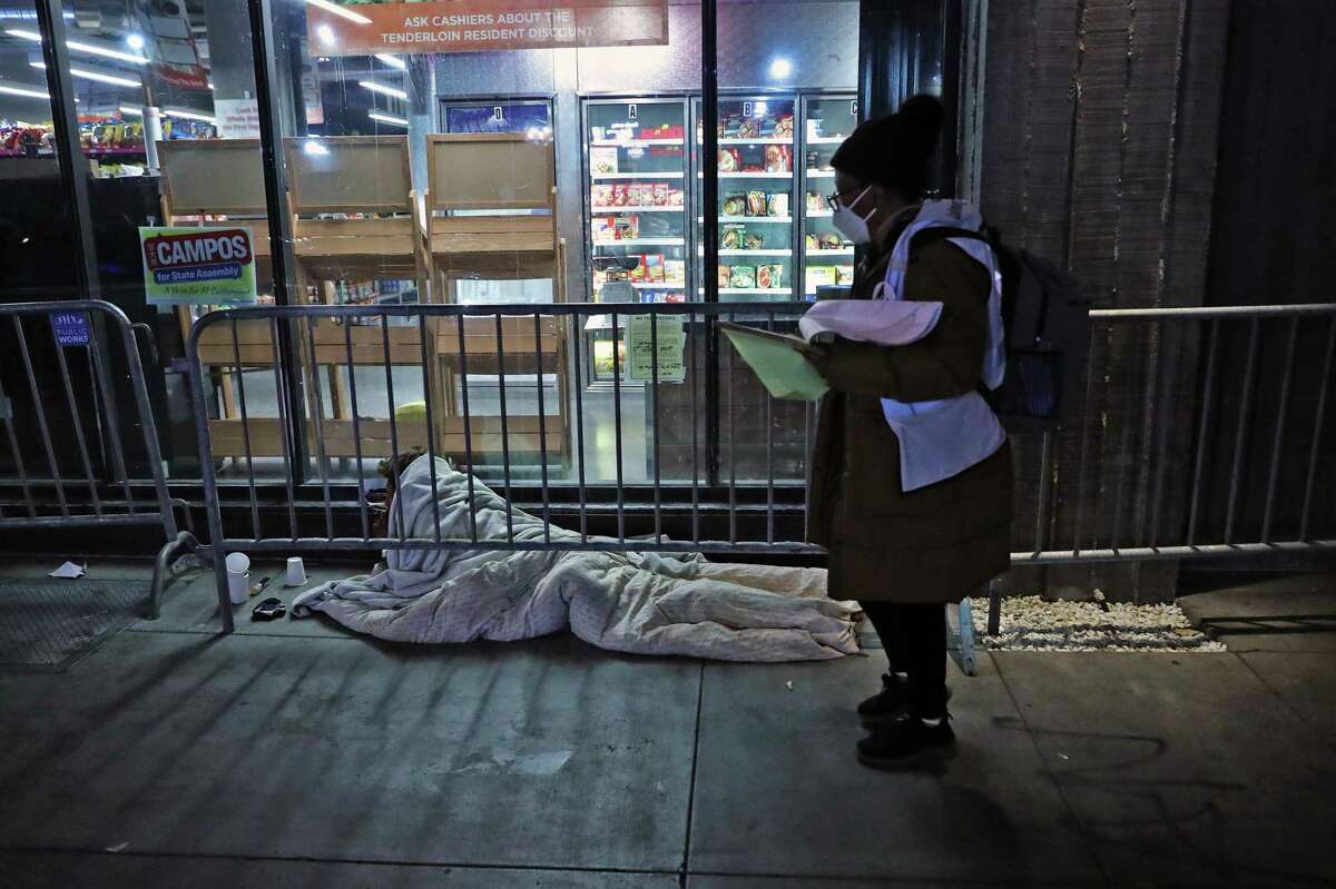 Tina O'Collins walks a homeless man on Turk Street during Point In Time one-night homeless count in San Francisco, Calif., on Wednesday, February 23, 2022.