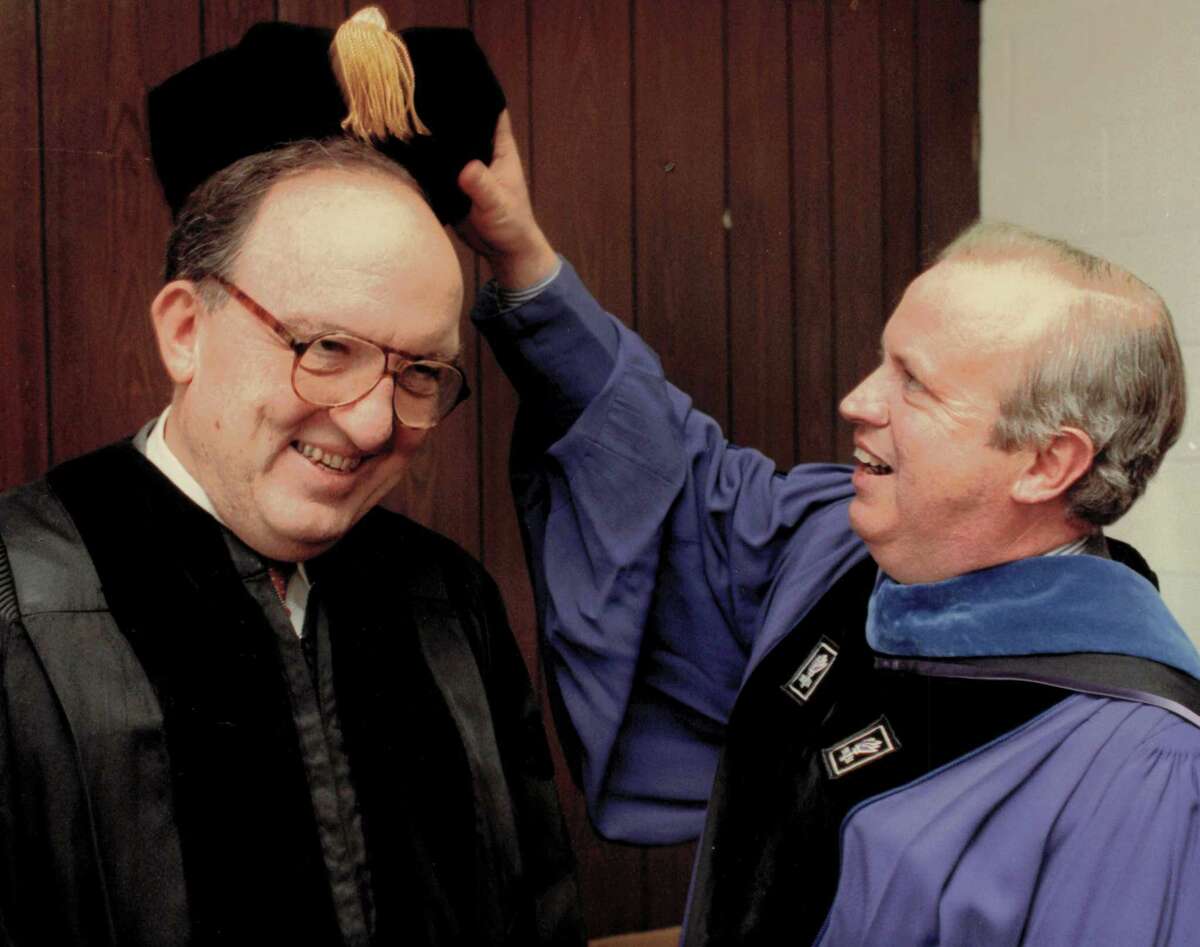 University of New Haven President Lawrence J. DeNardis helps baseball commissioner Francis Thomas Vincent with his scholars cap prior to the start of the 1992 commencement when Vincent received an honorary degree of Doctor of Laws and gave the commencement address.