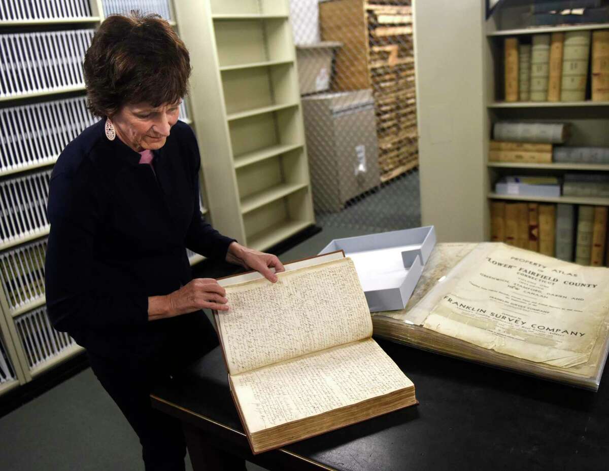 City & Town Clerk Lyda Ruijter shows one of the three historic town record books that have been preserved at the Town Clerk's office at the Government Center in Stamford, Conn. Monday, May 2, 2022. The clerk's office has dozens of books containing historic town records that are hundreds of years old and need to be preserved before they get even more damaged. The city has done three books thus far, but the process is quite pricey as each book cost more than $10,000 to preserve, rebind, and digitize.