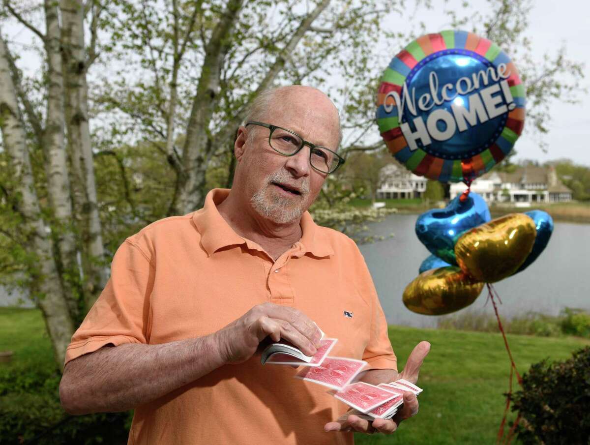 Magician Bill Herz poses beside a "Welcome Home" balloon outside his home in the Riverside section of Greenwich, Conn. Thursday, May 5, 2022. Herz and his family recently traveled to Poland for two weeks to perform magic shows for Ukrainian refugees.