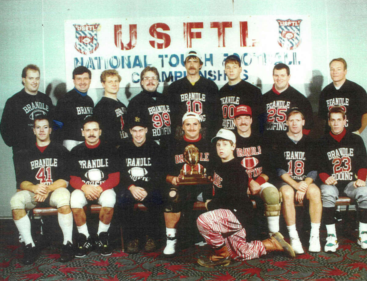 Brandle Roofing's 1992 football team poses in front of its national championship banner.