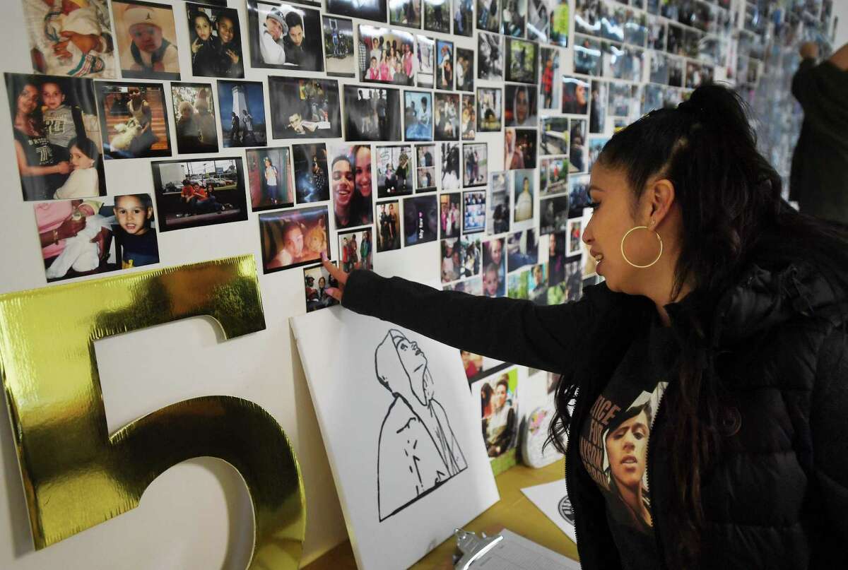 Natasha Tosado, mother of Jayson Negron, points to a photo of her son with his childhood teddybear on a wall of photos at The Nest Art Factory in Bridgeport, Conn. on Saturday, May 7, 2022. Jayson Negron was shot and killed five years ago while driving in a stolen car by Bridgeport police officer James Boulay.