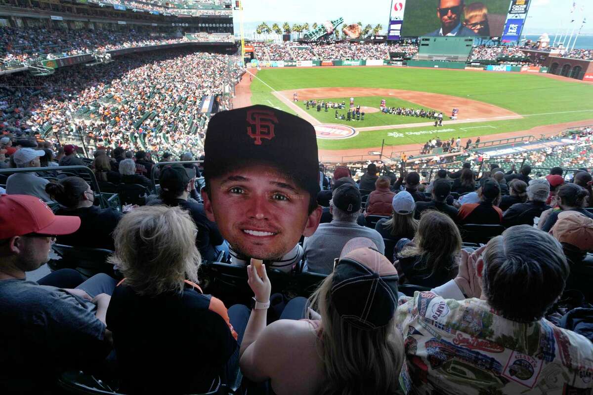 A fan holds an image of former San Francisco Giants catch Buster Posey as Posey is honored for his career, before the team's baseball game against the St. Louis Cardinals on Saturday, May 7, 2022, in San Francisco. (AP Photo/Tony Avelar)