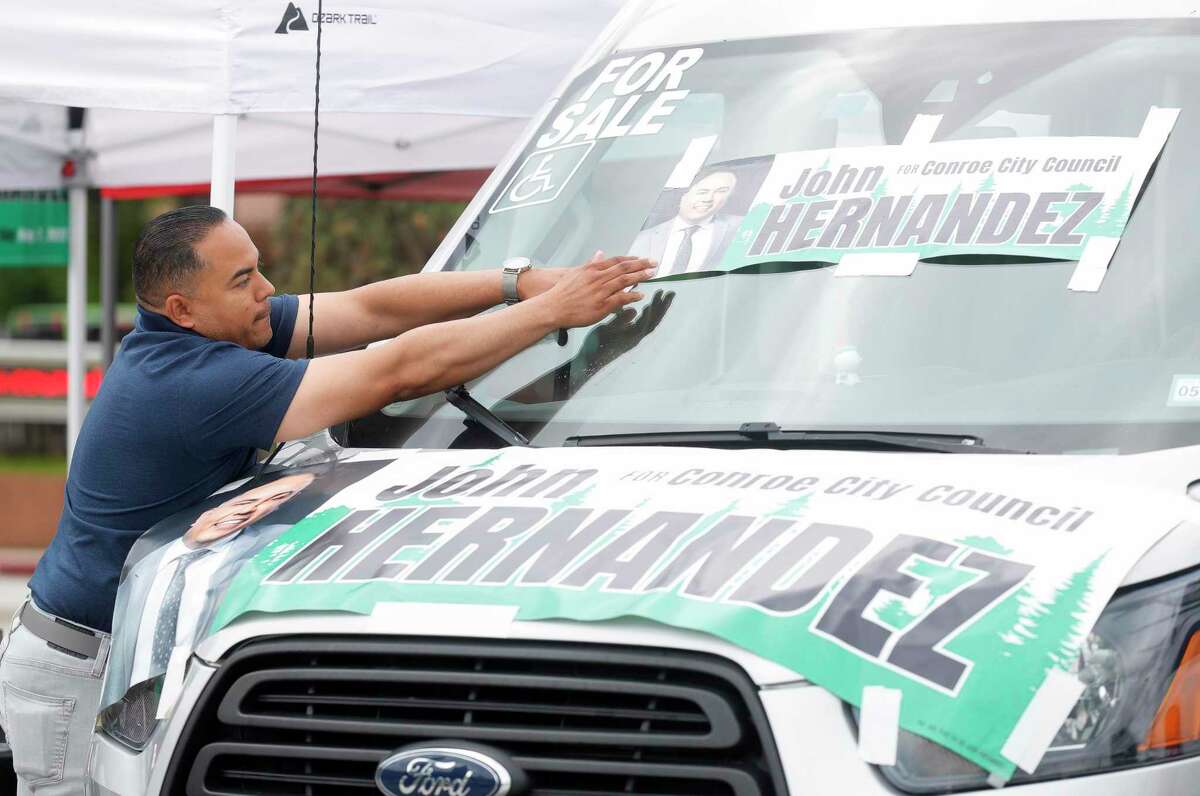 Conroe City Council candidate John Hernandez tapes a sign to his van on the second day of early voting at the Montgomery County Central Library, Tuesday, April 26, 2022, in Conroe.