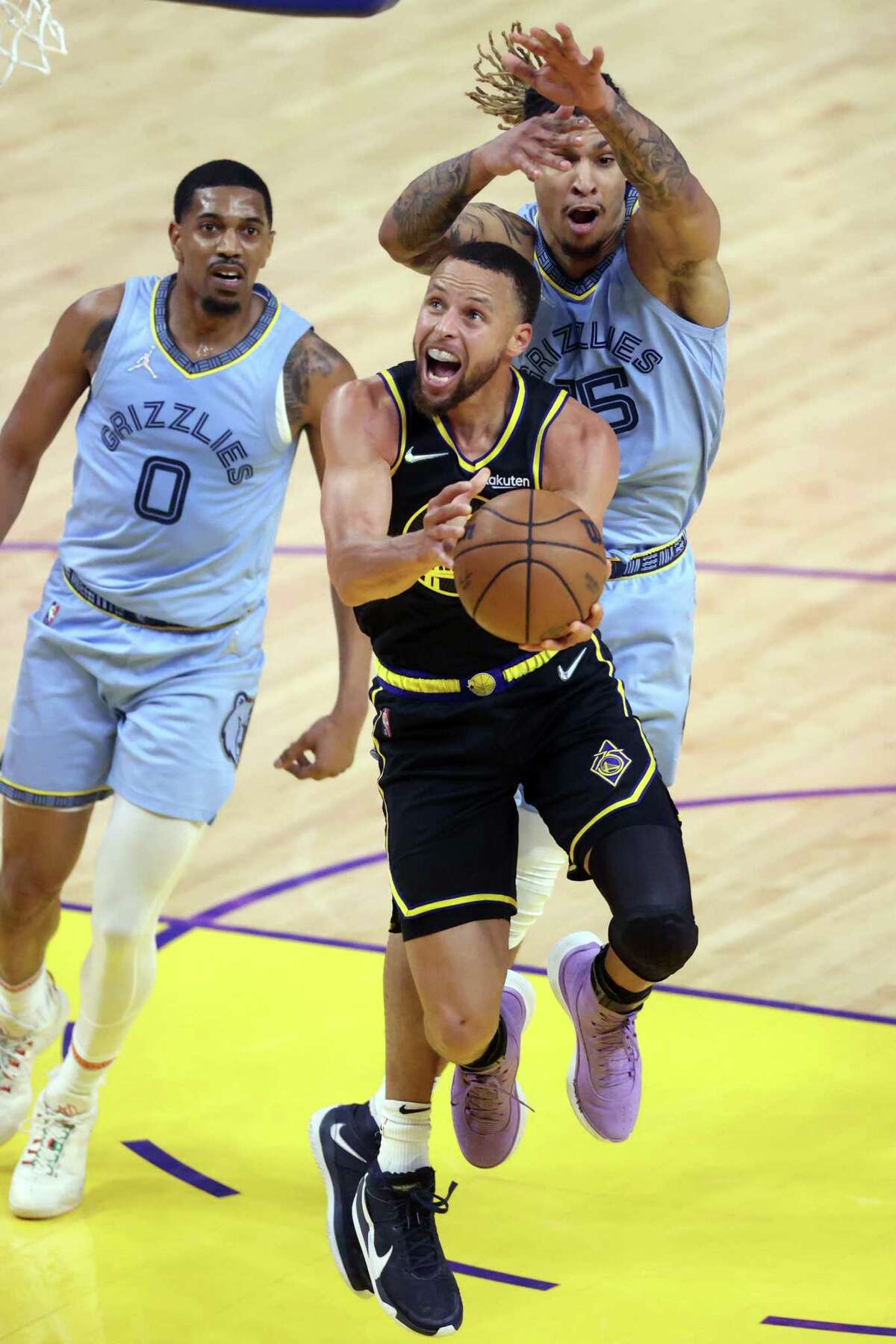 Golden State Warriors’ Stephen Curry scores in front of Memphis Grizzlies’ Brandon Clarke and De’Anthony Melton in 4th quarter during Game 3 of NBA Western Conference Semifinals in San Francisco, Calif., on Saturday, May 7, 2022.