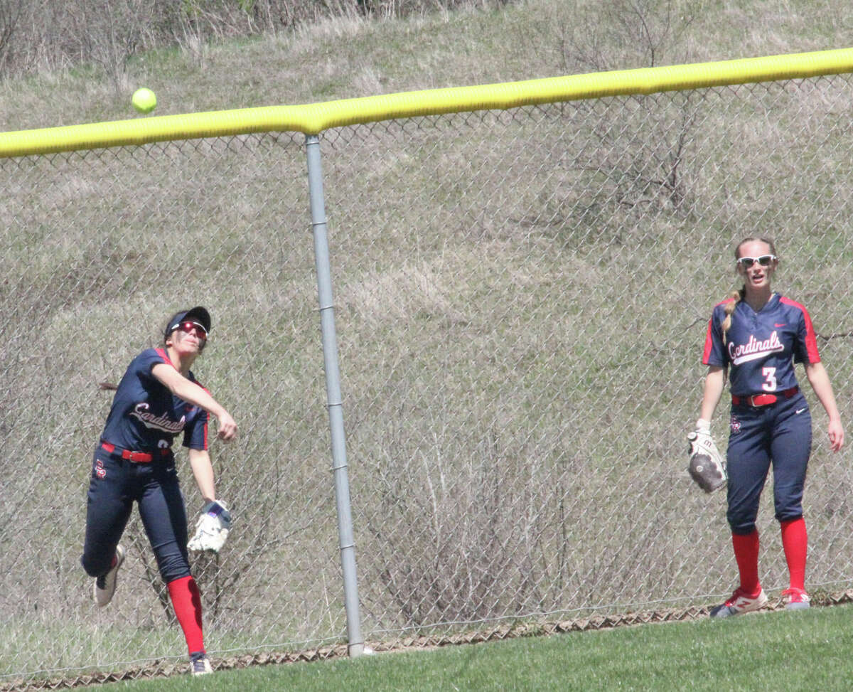Big Rapids' leftfielder Mackenzie Ososki  (left) throws the ball in against Benzie Central on Saturday after an extra base hit to the fence. At right is center fielder Hanna Smith.