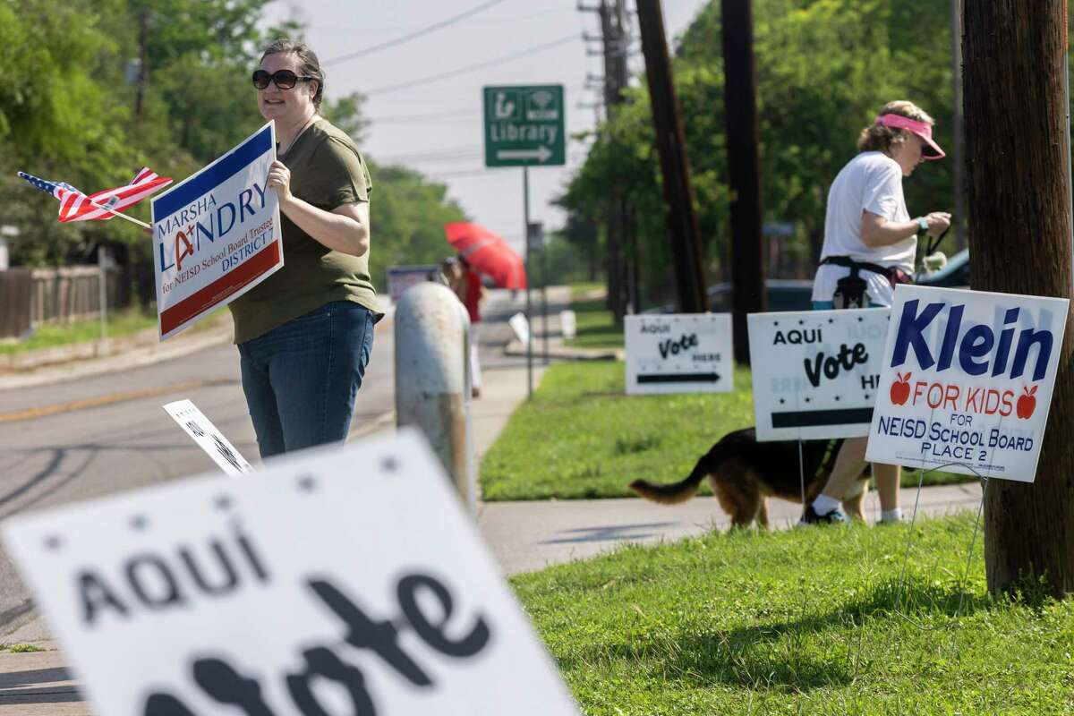A supporter of NEISD board candidate Marsha Landry holds a sign outside Brook Hollow Library on Saturday. People voted on the city's bond package, two state propositions on property taxes, school board seats, bond proposals and suburban city council elections.
