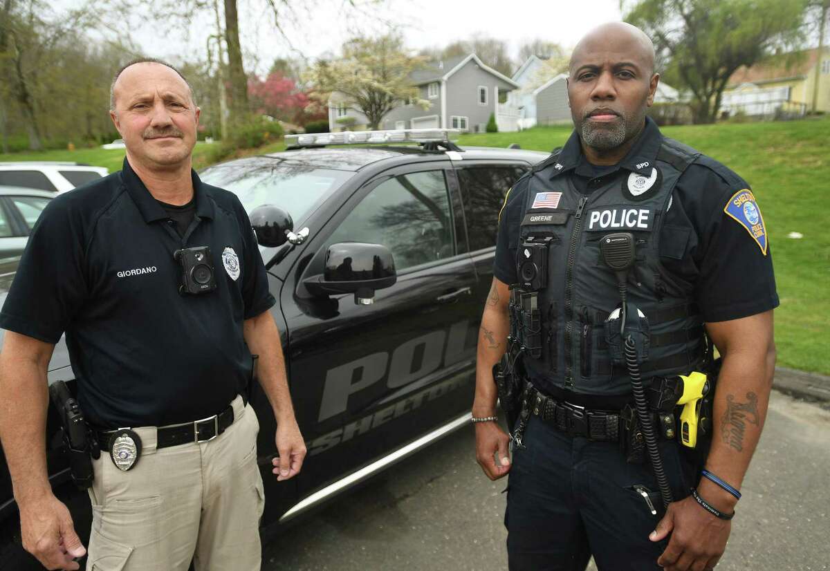 Shelton Police Officers John Giordano, left, and Tim Greene wear the newly issued body cameras outside the Shelton Police Department in Shelton, Conn., on Friday, May 6, 2022. Giordano is the police union president.