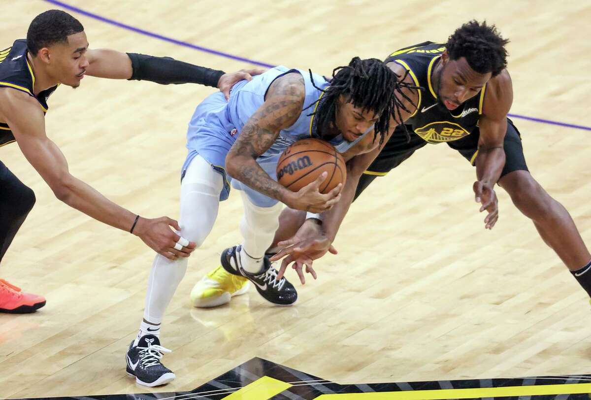 The Warriors’ Jordan Poole (left) and Andrew Wiggins defend the Grizzlies’ Ja Morant late in Game 3. Shortly afterward, Morant left the game with a knee injury.