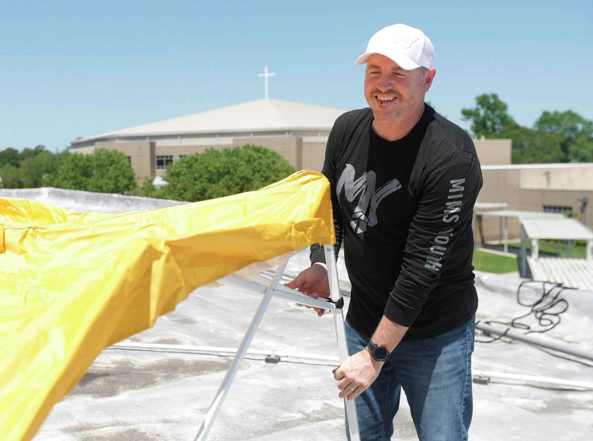 Larry Daigle, youth minister at Mims Baptist Church, sets up his tent and other supplies for his evening stay on the roof of the church's youth ministry building, Wednesday, April 27, 2022, in Conroe. Daigle spent 24 hours on the roof to complete the challenge he set for the youth ministry if they got 150 participants for this year's youth camp.
