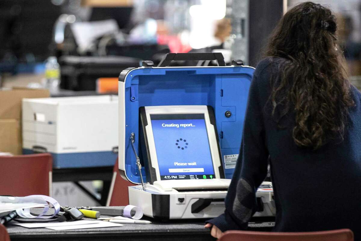 A Harris County election staffer runs a report on a ballot scanning machine after it came in to the Harris County Election Technology Center Wednesday, March 2, 2022 in Houston.