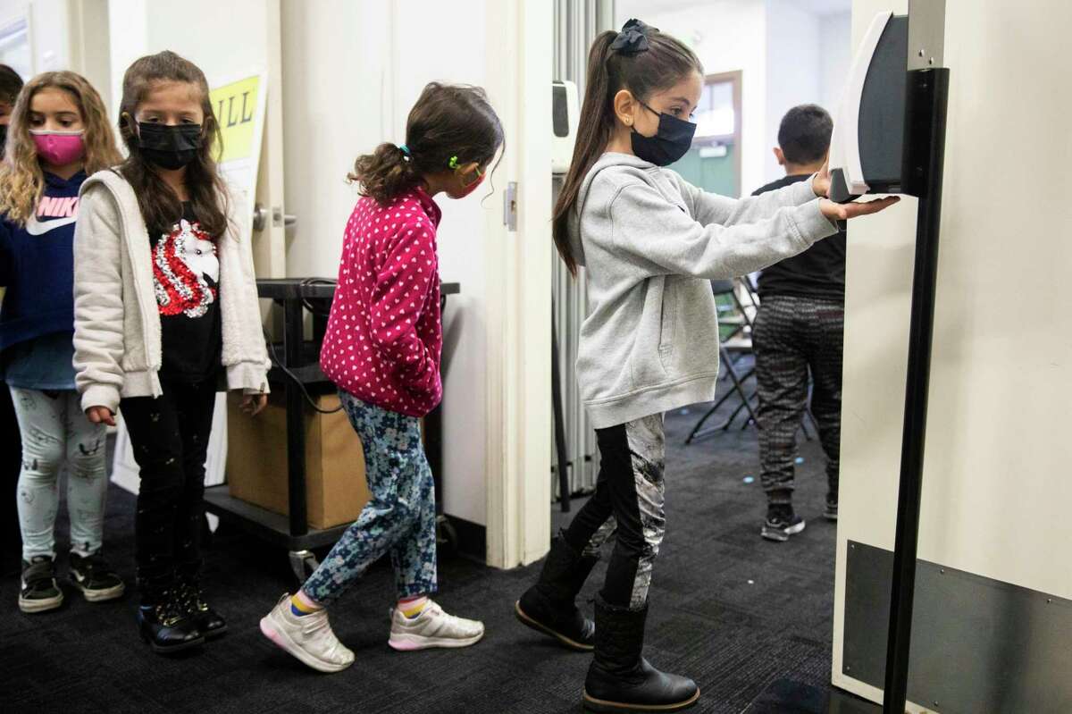 First-graders at Roosevelt Elementary in Burlingame sanitize their hands.  Will masks help them if everyone is not wearing them?