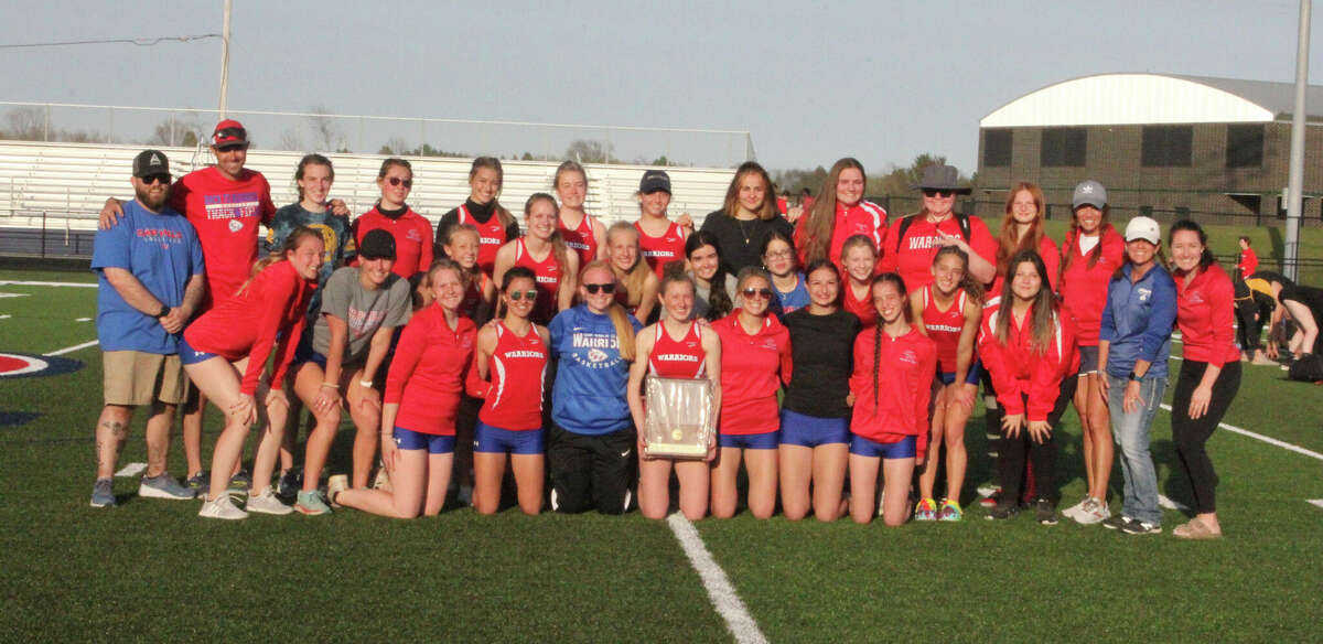 Chippewa Hills girls track team hold up their 19 straight league title trophy on Monday.