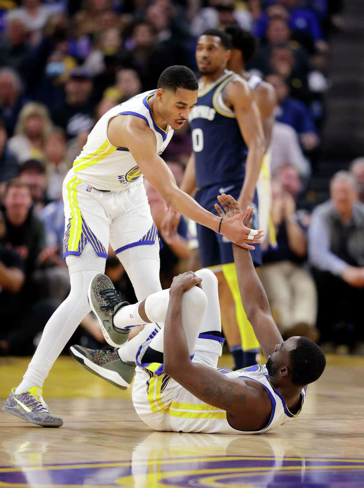 Jordan Poole (3) helps up Draymond Green (23) in the first half as the Golden State Warriors played the Memphis Grizzlies in Game 4 of the Western Conference Semifinals of the NBA Playoffs at Chase Center, in San Francisco, Calif., on Monday, May 9, 2022.