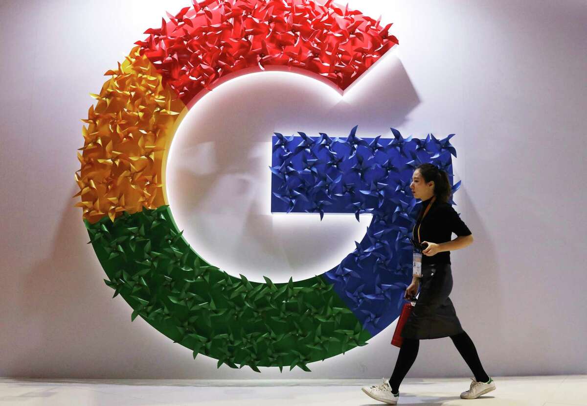 FILE - A woman walks past the logo for Google at the China International Import Expo in Shanghai on Nov. 5, 2018. (AP Photo/Ng Han Guan, File)