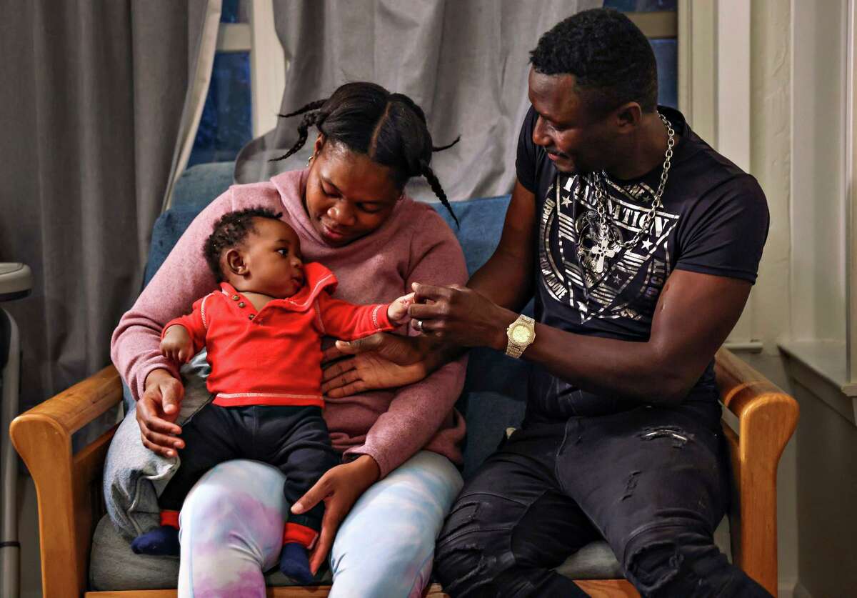 Jean-Simon Colas (right) meets his infant son Quenndly for the first time as Colas’ wife Diatha Bell holds him in their Alameda apartment on Monday, May 9, 2022. The family was separated for nine months.