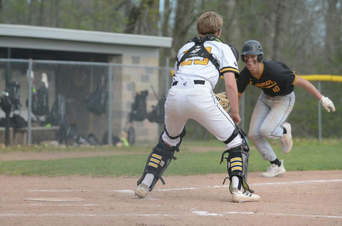 Law’s Mike Merchant looks at Hand catcher Connor Powell before he dove to score a run during a game on Tuesday.