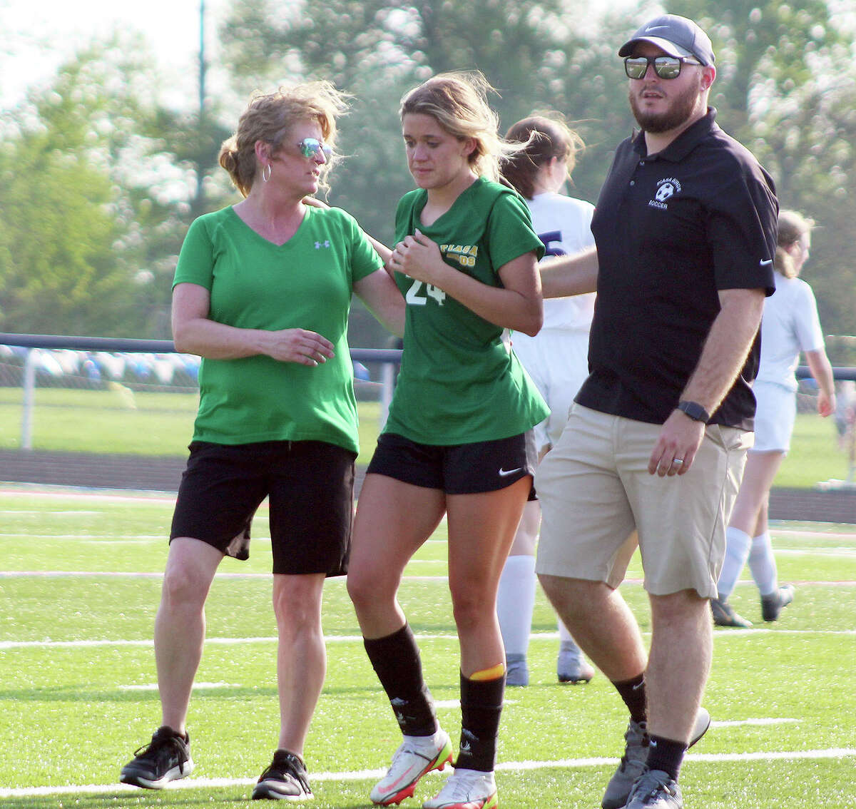 Southwestern's Mac Day is helped off the field by assistant coach Betty Schiller and head coach Tyler Hamilton. Day had been injured in the second half after being struck in the head by the ball. She was not allowed to return by IHSA rules because there was no trainer or qualified personnel  to examine her.