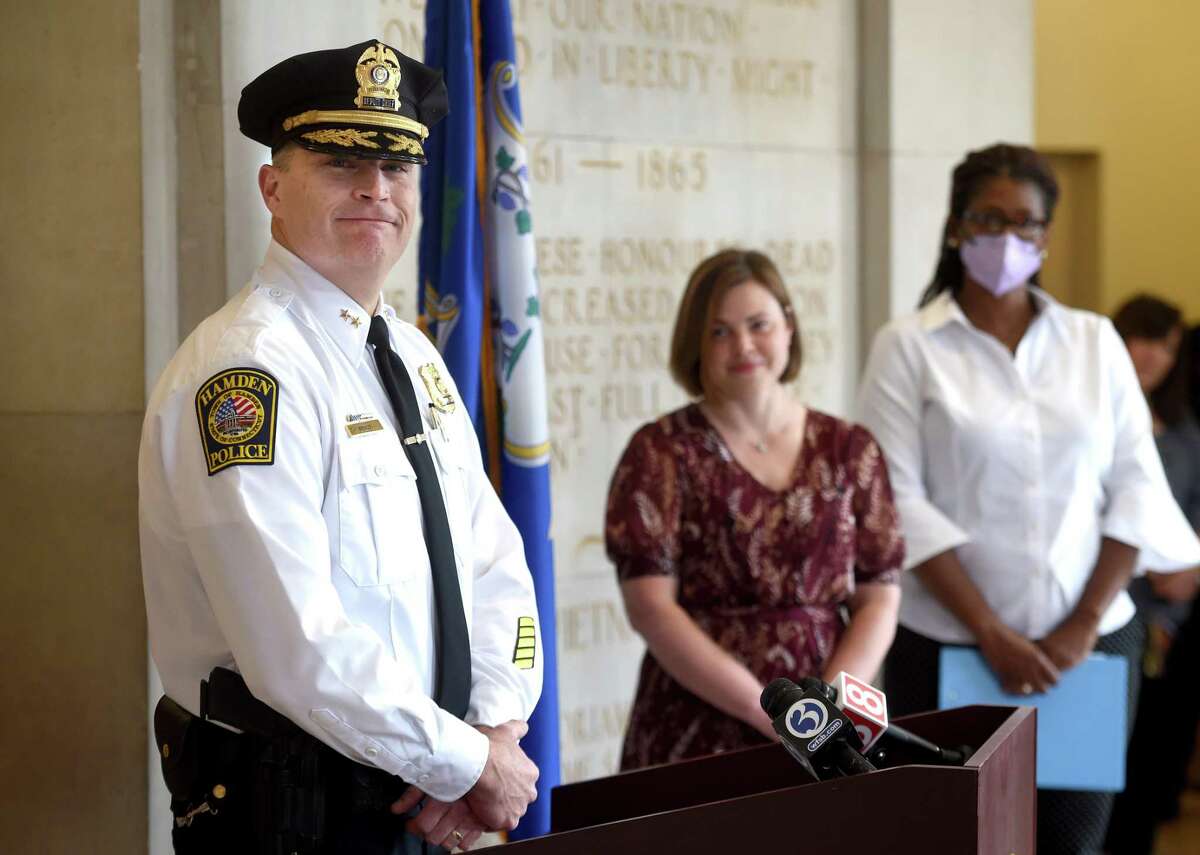 Timothy Wydra, left, speaks after being sworn in as deputy chief of the Hamden Police Department at a ceremony at Memorial Town Hall Wednesday. From left are Wydra, Mayor Lauren Garrett and Town Clerk Karimah Mickens.
