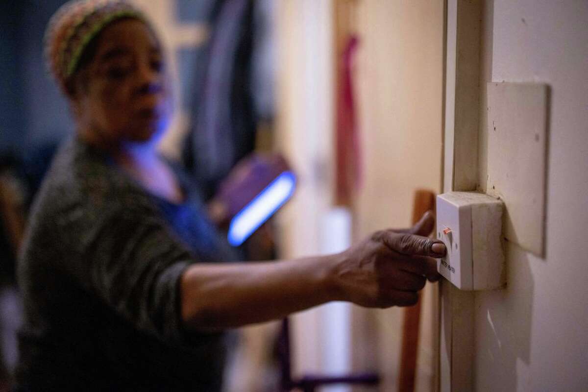 Doreen Thompson turns off her water heater as she limits her use of heating to keep up with her increasing energy bills. (Photo by TOLGA AKMEN/AFP via Getty Images)