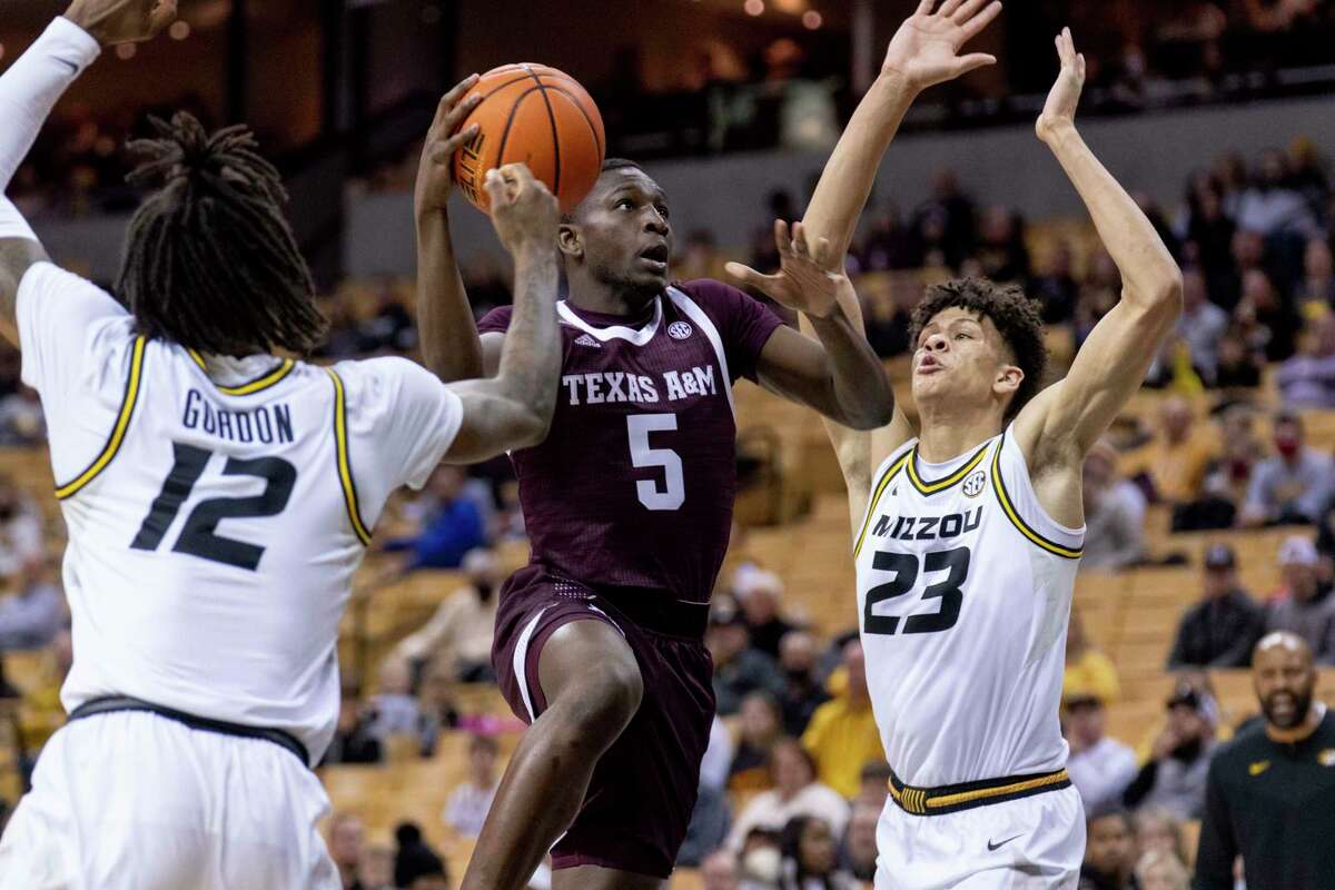 Texas A&M's Hassan Diarra, center, shoots between Missouri's Trevon Brazile, right, and DaJuan Gordon, left during the first half of an NCAA college basketball game Saturday, Jan. 15, 2022, in Columbia, Mo.