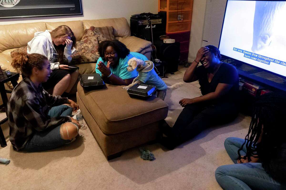 Jhonelle Bean, center, wearing a blue shirt, enjoys a night of games with her friends. Bean has created a tight-knit group of friends that play music and worship together. Nearly three years ago, Bean moved out of the San Antonio home where she had previously suffered abuse.