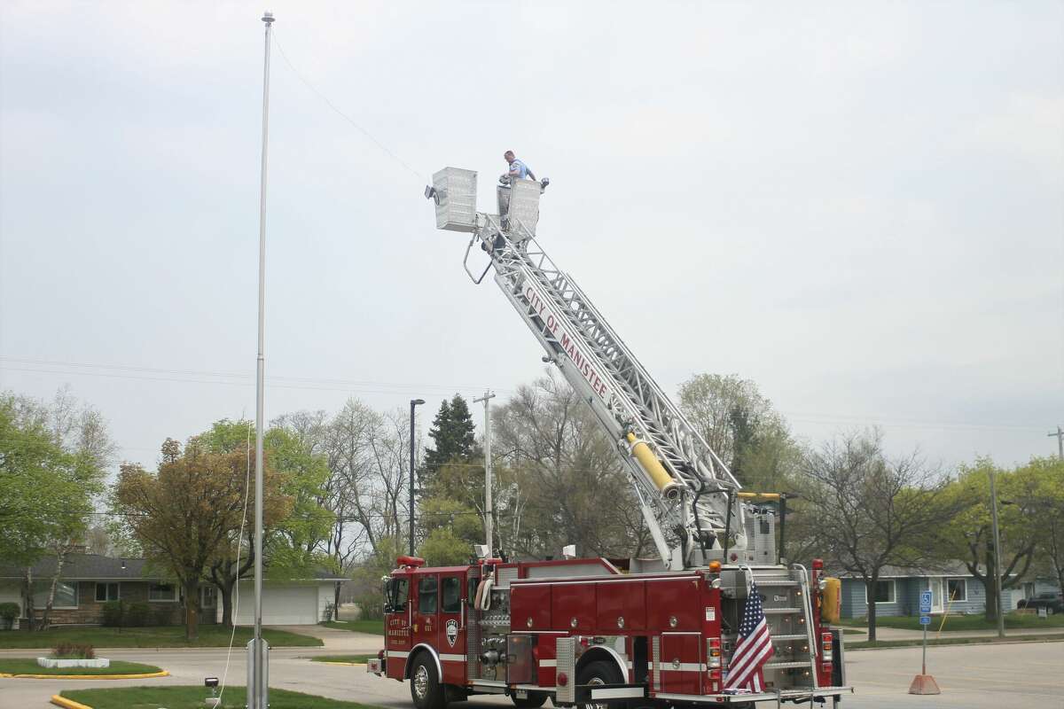 Mark Cameron, Manistee fire chief, comes down after attaching a cable to the Armory Youth Project flag pole.