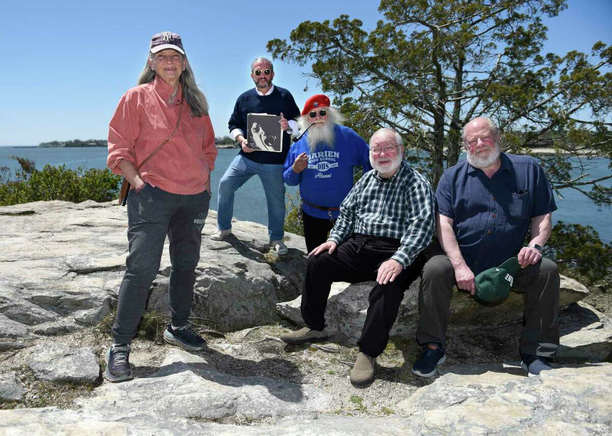 Darien High School Class of 1970 classmates, from left, Nina Miller, Vic Capellupo, Rich Glica, Drew Papsun and Dave Miller together with their yearbook at Weed Beach in Darien on Monday, May 9. The DHS Class of 1970 50 year reunion was postponed two years because of COVID, but after much rescheduling it will be held the weekend of July 23 with a gathering at the VFW, dinner and dance at Wee Burn Country Club, and lunch at Weed Beach.
