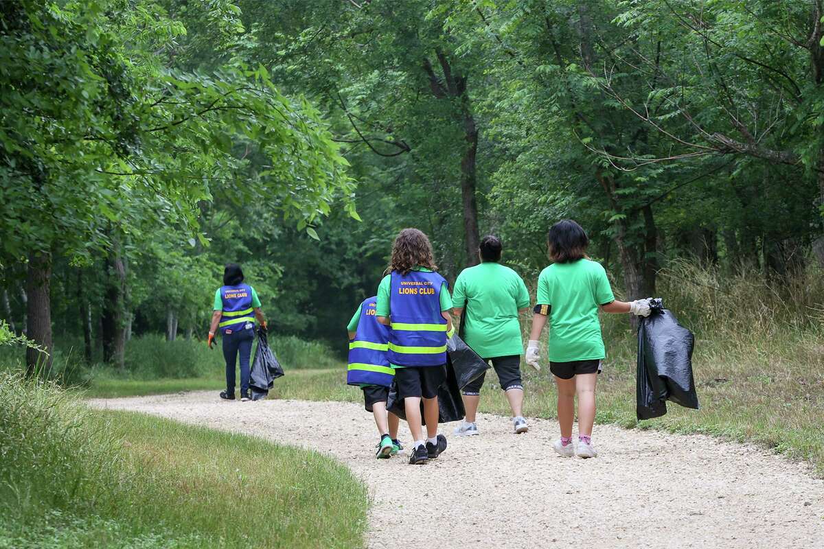 Volunteers head out with bags in hand to clean up the trails along Cibolo Creek at Universal City Veterans Park for an organized park cleanup on April 30.