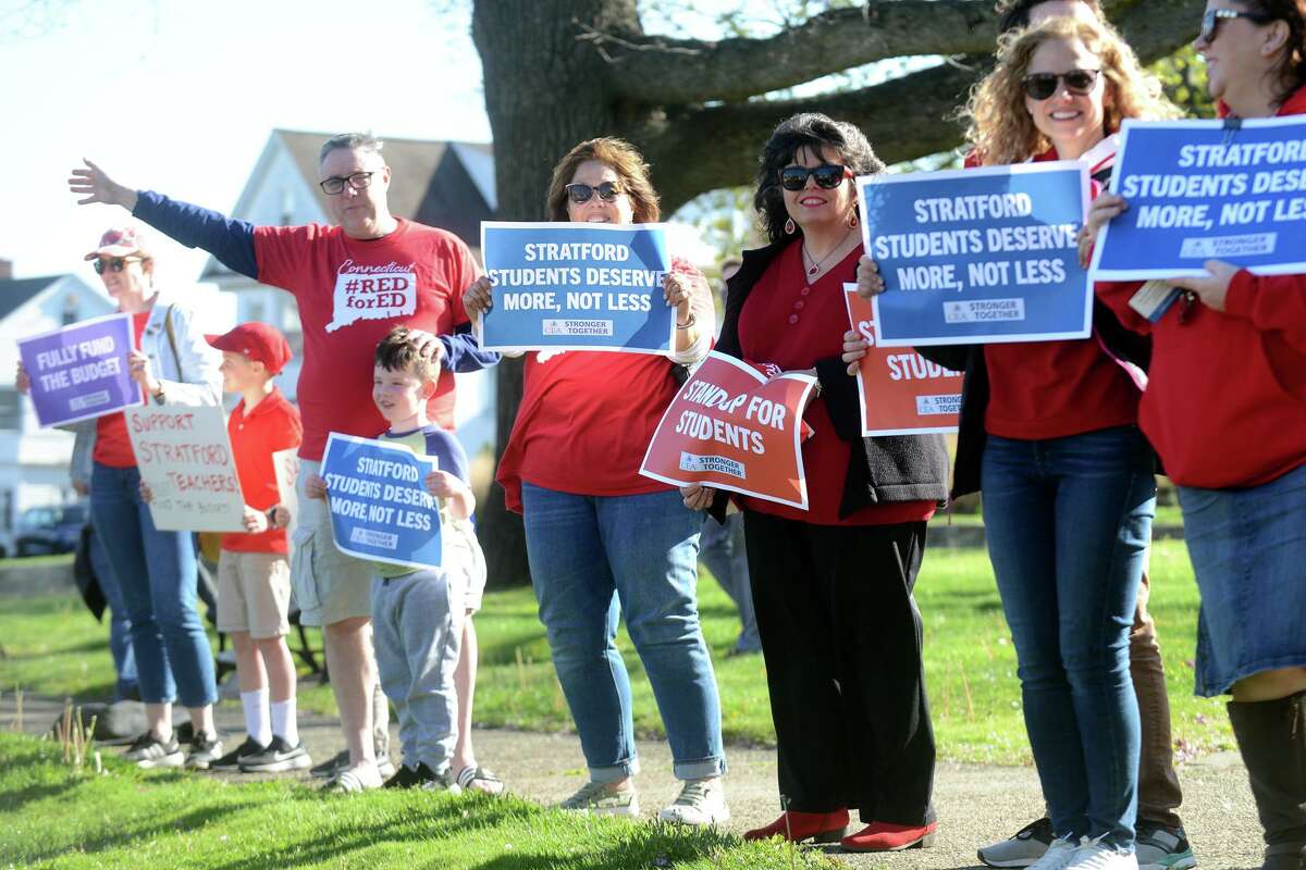 Teachers, parents and students wave to passing drivers during a rally outside of Town Hall, in Stratford, Conn. May 9, 2022.