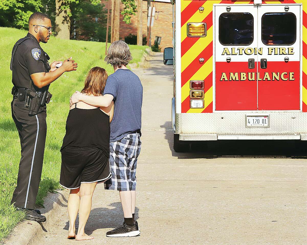 John Badman|The Telegraph Two people watch as an Alton Fire Department ambulance prepares to transport two carbon monoxide victims to the hospital Thursday morning.
