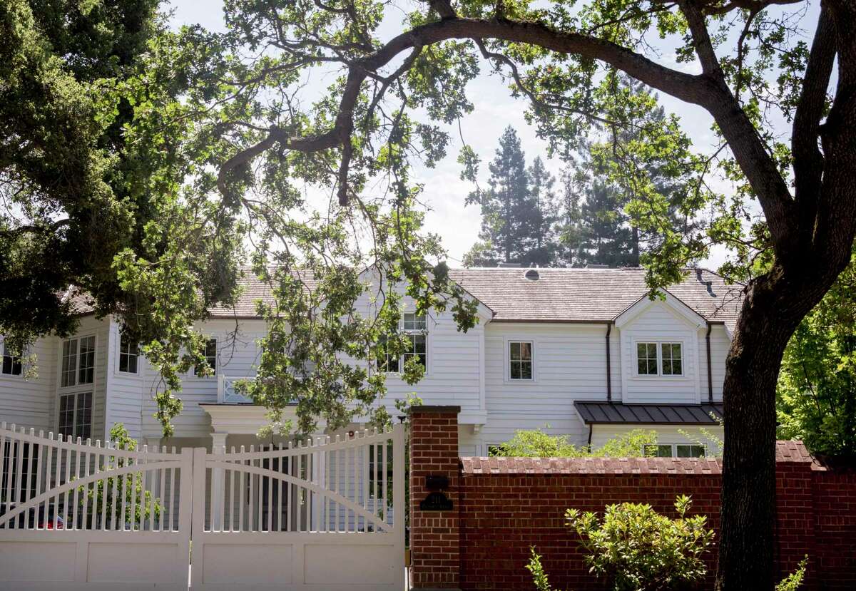 A large home is seen behind a white gate along Polhemus Avenue in Atherton, Calif. Atherton will consider allowing the construction of town homes for the first time in the 99-year history of the exclusive Peninsula commuter community as it struggles to meet a state mandate to add housing.