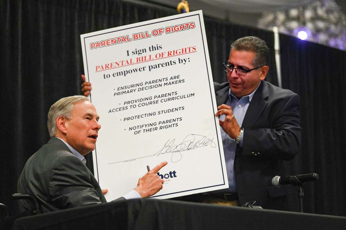 Texas Governor Greg Abbott, left, signs a giant copy of his Parental Bill of Rights as Rep. John Lujan holds it for him at the PicaPica Plaza Event Center on the Southside of San Antonio on Monday, May 9, 2022. Several hundred Republican faithful attended the event.