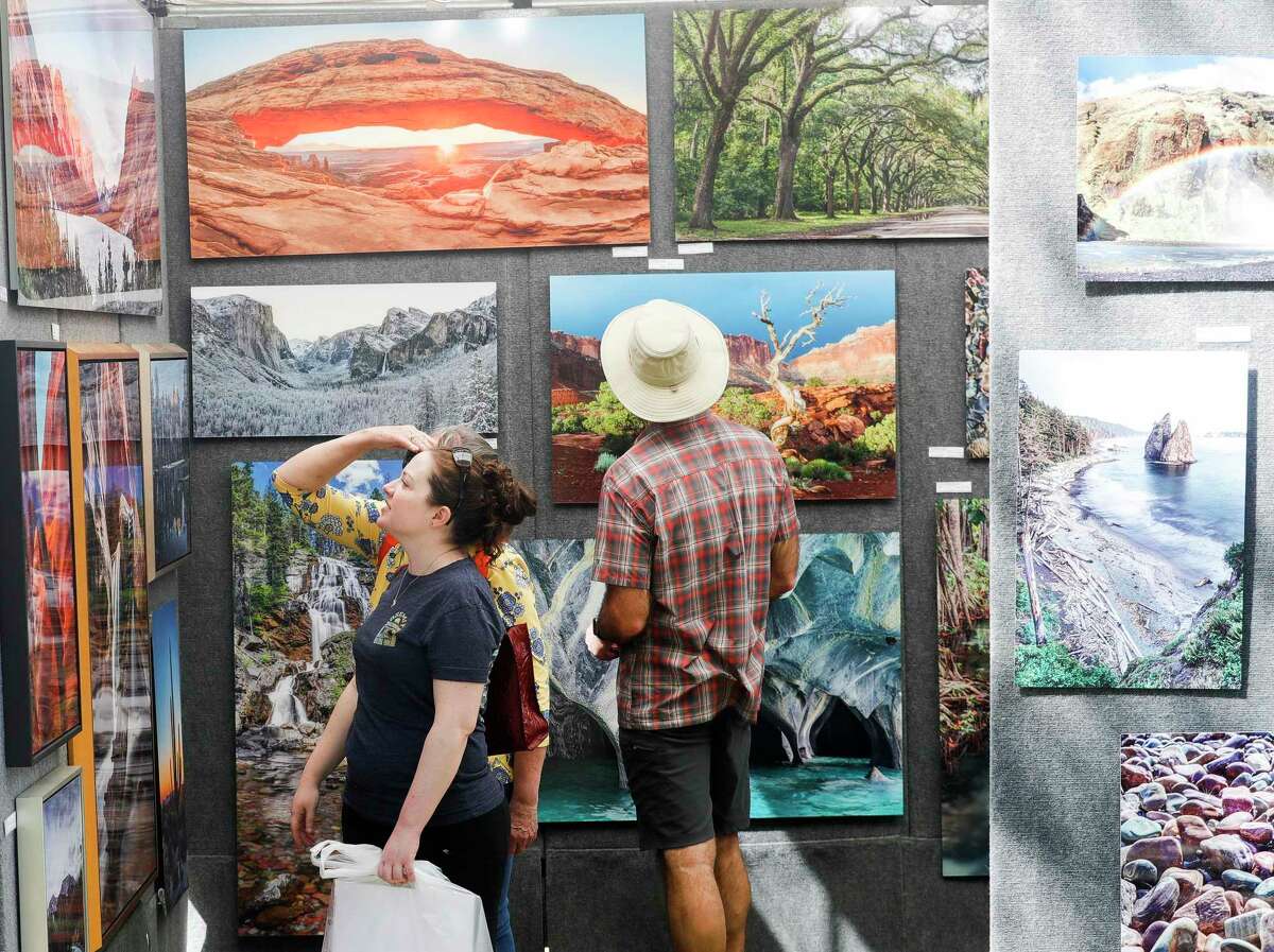 Caitlyn King goes through a photos gallery by Glenn Lewis during The Woodlands Waterway Arts Festival at Town Green Park, Saturday, April 9, 2022, in The Woodlands.