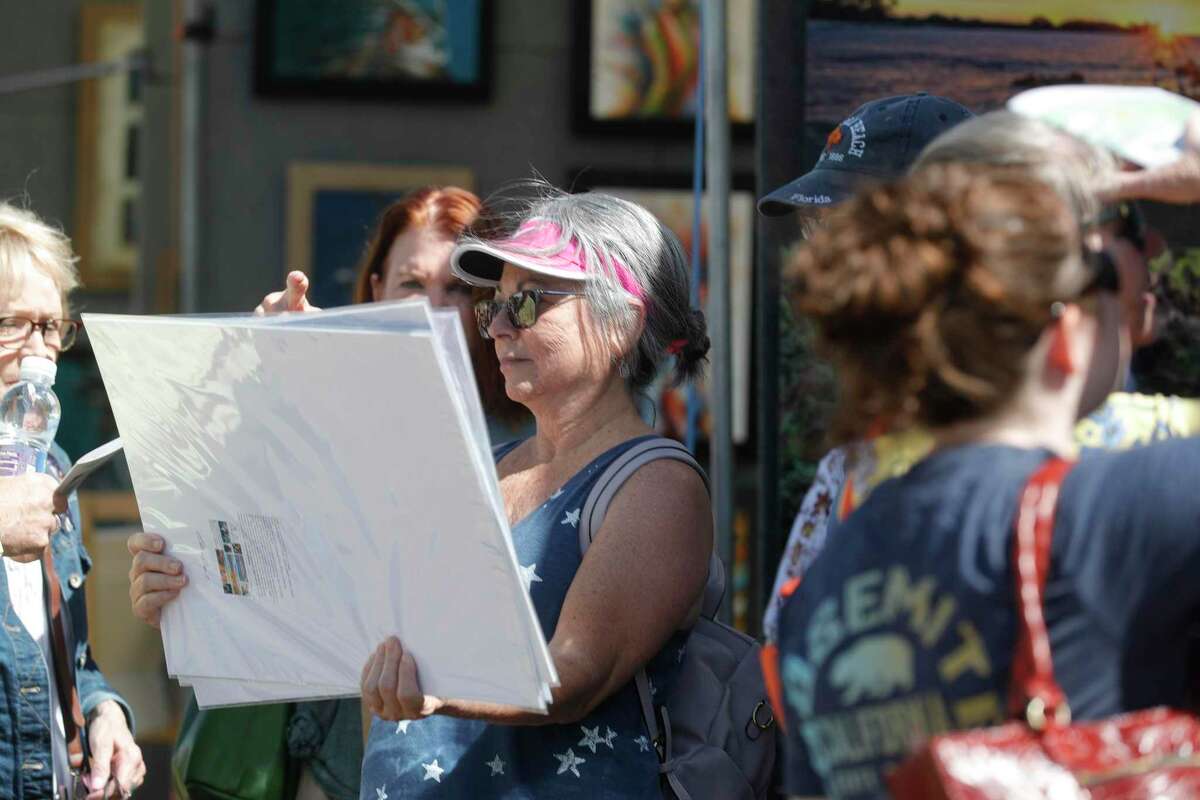 Gail Wescott looks through artwork she purchased during The Woodlands Waterway Arts Festival at Town Green Park, Saturday, April 9, 2022, in The Woodlands.