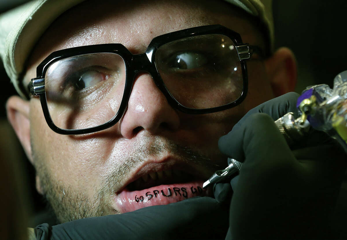 Joseph Knucklz gets a "Go Spurs Go" tattoo on the inside of his lower lip by "Criket" at D's Body Ink on Friday, June 13, 2014.