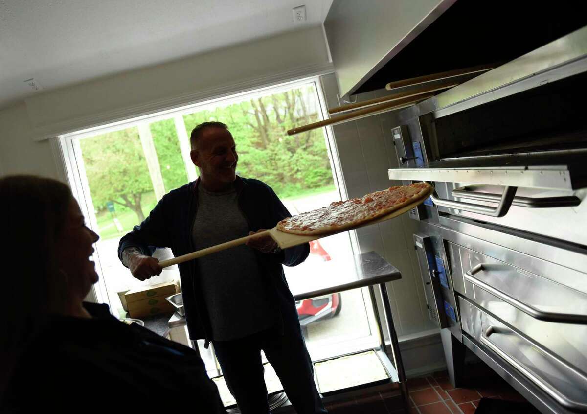 Owners Robyn and Michael Bordes take a pizza out of the oven at Constantino's pizza and ice cream restaurant in Greenwich, Conn. Thursday, May 12, 2022. Robyn and Michael Bordes recently opened the restaurant at the location of the former Stateline Deli at 699 W. Putnam Ave.