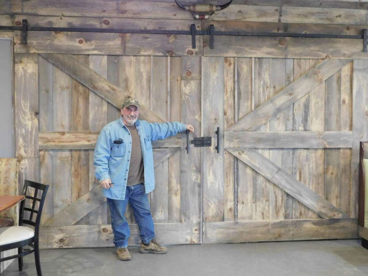 The Mill House Cafe & Bar is opening soon on Winsted Road in Torrington. Fred Rizvani, owner, stands before large sliding doors he built of antique barnboard inside his new restaurant.