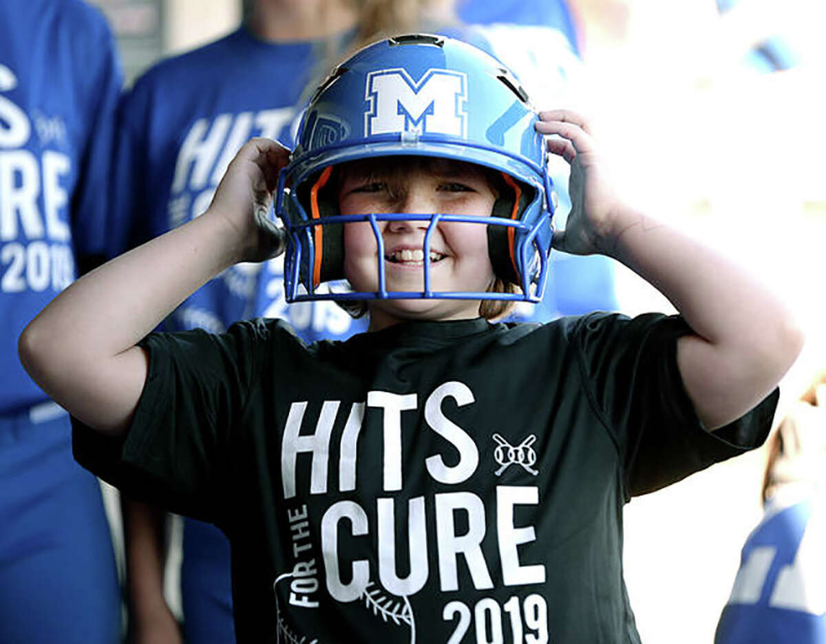 Karly Rathbun, then 10, tries on a Marquette Catholic High softball helmet at the 2019 Hits for The Cure Tournament. Karly will be at Saturday's Marquette-CM game.
