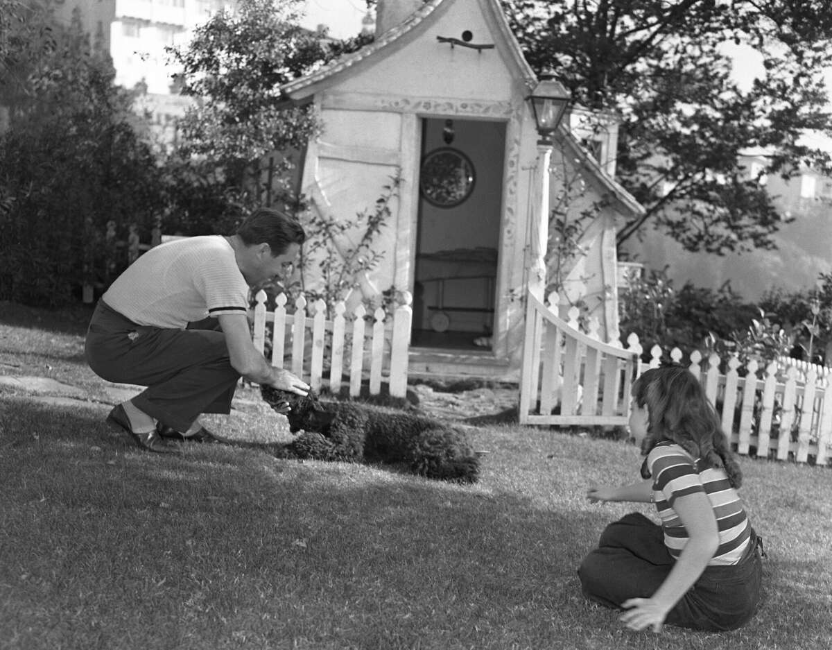 Walt Disney plays with his daughter and his dog in his garden circa 1940 in Los Angeles.