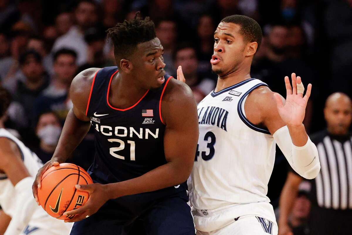 UConn’s Adama Sanogo, left, looks to pass the ball while defended by Villanova’s Eric Dixon during the Big East Tournament at Madison Square Garden on March 11 in New York.
