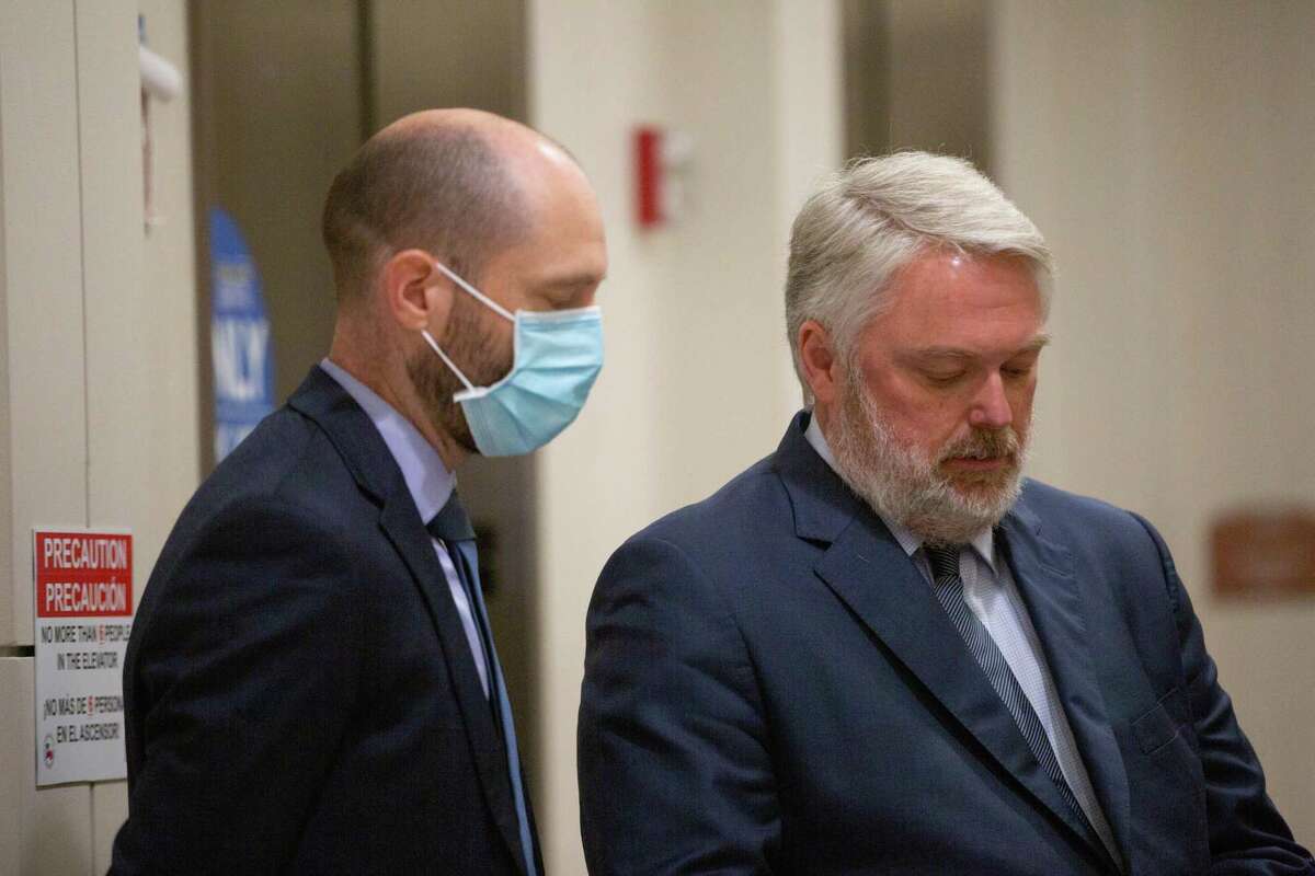 Former county worker, Aaron Dunn, left, who no longer works for County Judge Lina Hidalgo and Houston attorney Andy Drumheller, right, wait for an elevator at the Harris County Criminal Courthouse after appearing at a bond hearing at the 174th Criminal District Court, Friday, May 13, 2022, in Houston.