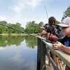 Above, Maddox Cota, 9, fishes from the pier along with other kids and adults during the annual “The Kids on the Lake” fishing event for special needs children on Weisinger Pond at the new Westside Park over the weekend in Conroe. At left, Josiah Clark, 9. Noah Clark, 14, and their father Robert Clark cast their lines into the lake.