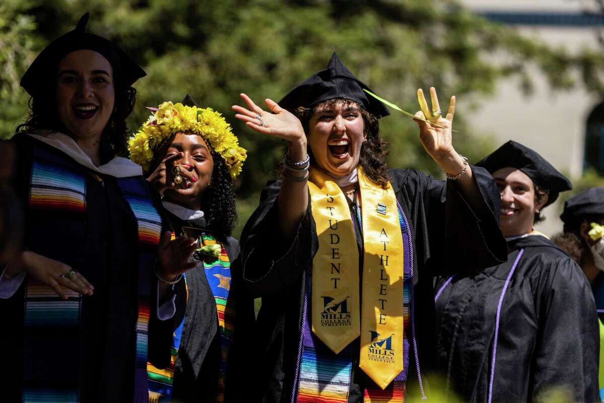 Graduates wave to the crowd from the stage during commencement at Mills College in Oakland.